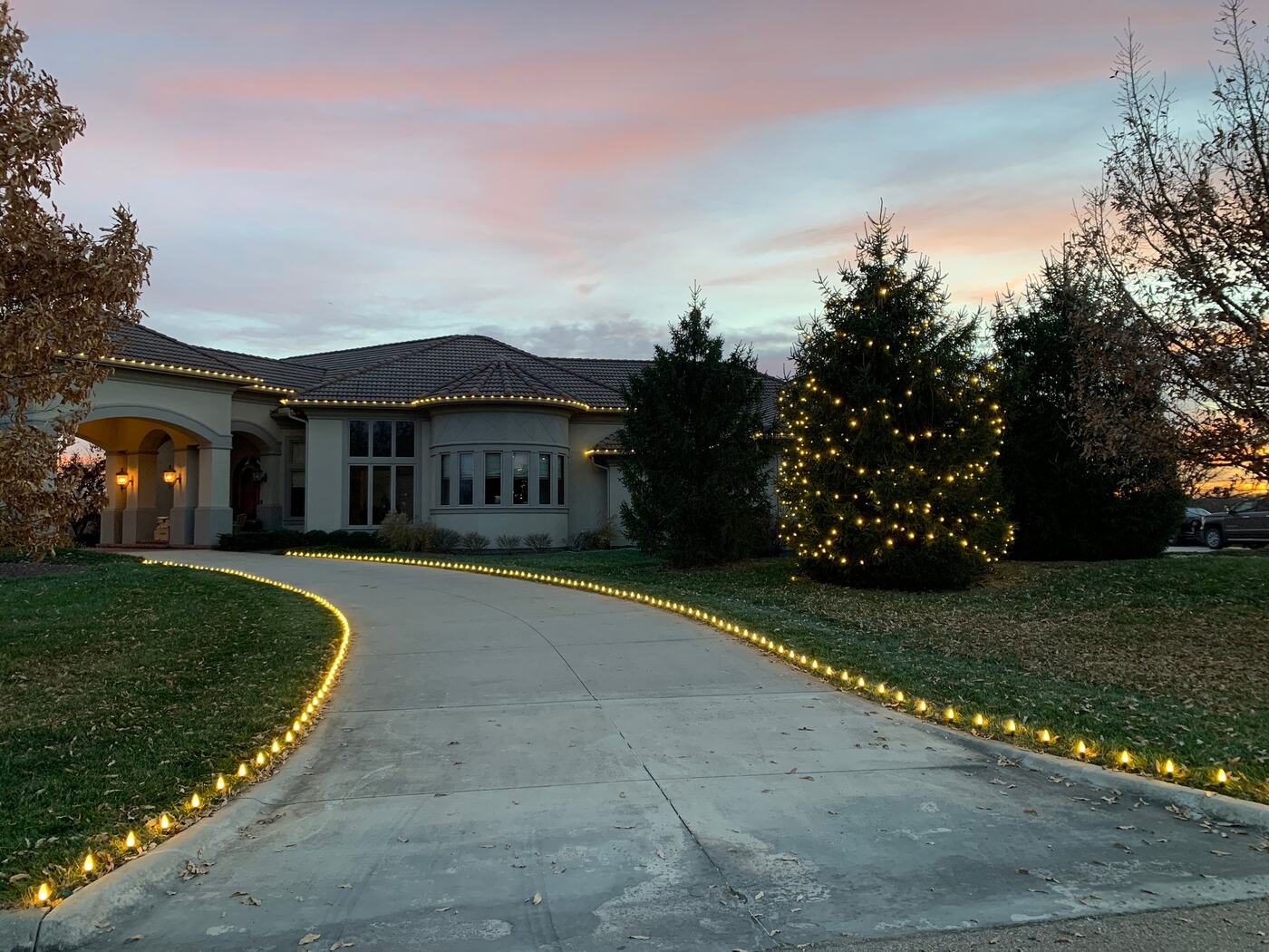 Lit driveway edges leading to a home at dusk