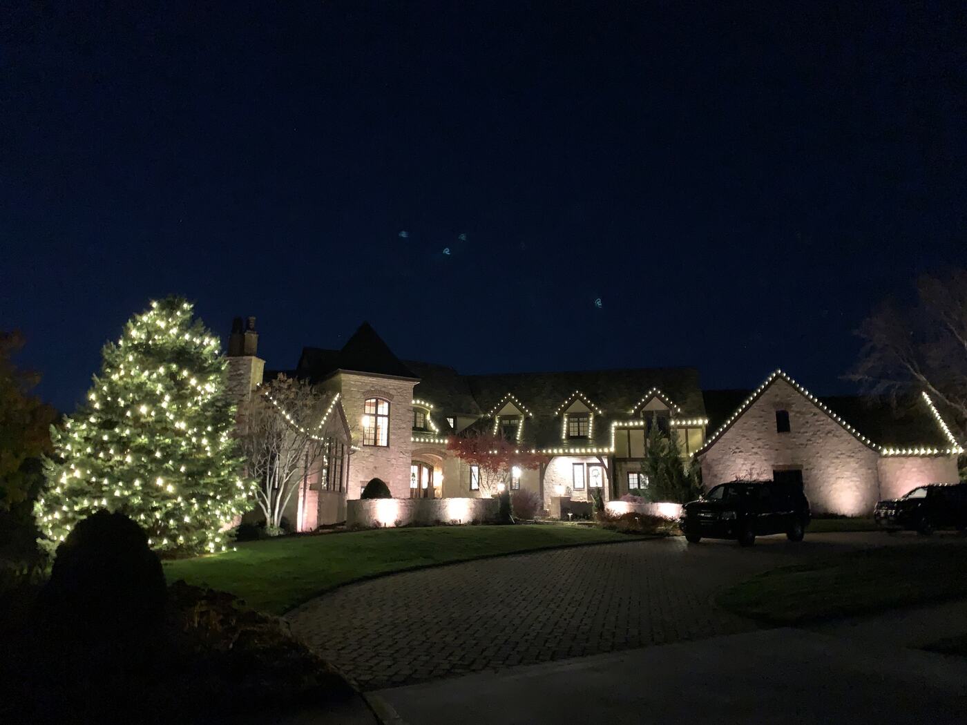 Estate home with a fully wrapped evergreen and warm white roofline