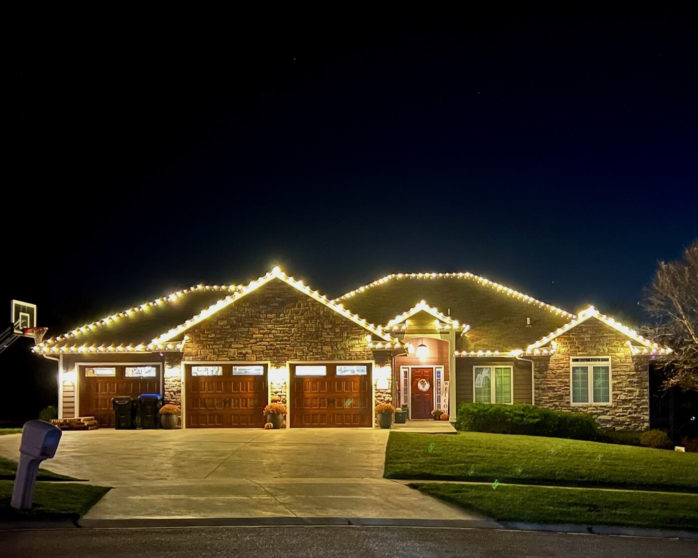 Stone ranch home with warm white roofline lighting